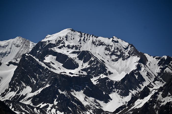 Close view of the snow-streaked north face of Om Parvat against a deep blue sky